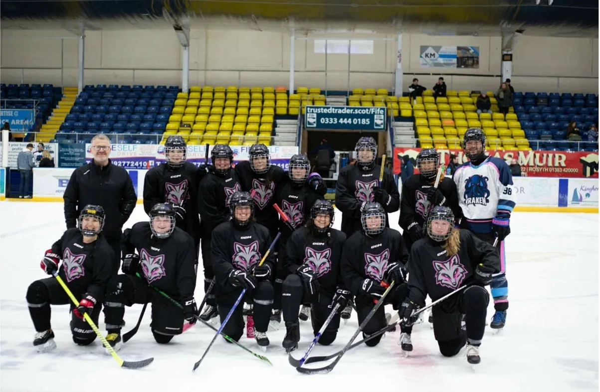 Arctic Foxes players in pink and black jerseys lined up on the ice at Fife Ice Arena